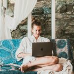 A woman sitting comfortably on a sofa using a laptop, depicting a serene remote work setup.